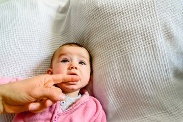 Beautiful and friendly 6 month old baby girl teething and biting to calm the pain