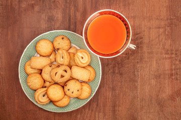 Danish butter cookies with a vintage tea cup, shot from above on a dark rustic wooden background with a place for text