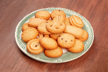 A plate of Danish butter cookies on a dark rustic wooden background