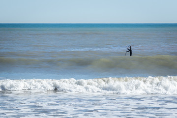 Surfer with paddle board catching the wave