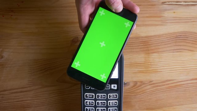 Closeup shoot of a payment terminal being used for payment by an app on the phone with green screen indoors