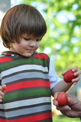 Excited boy knocking Easter eggs . Red Easter egg ready for egg tapping. Happy Easter!