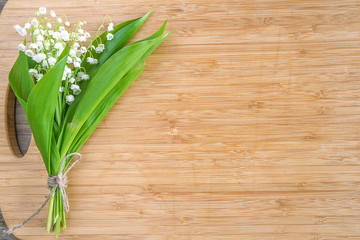 Bouquet of lilies of the valley on the wooden background with copy space