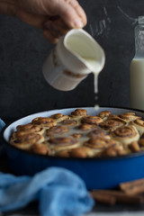  Baker putting sugar glaze syrup on to baked cinnamon buns