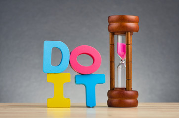 Do and don’t concept, colorful alphabet word DO IT on wooden desk over gently lit dark background