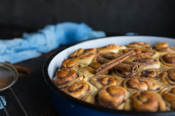 Cinnamon roll tart with sugar syrup in vintage baking pan on black background