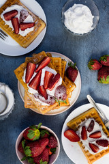 Traditional belgium soft waffles with strawberries and powdered sugar on dark background