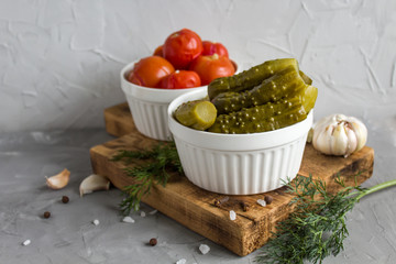 Marinated tomatoes with garlic, dill and spices in a plate on a gray background