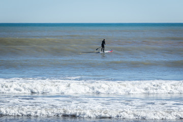 Surfer with paddle board catching the wave.