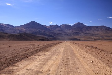 Fototapeta na wymiar Straight endless dirt road in Atacama desert, Chile