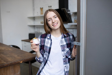 Beautiful girl takes yogurt from the fridge. Athletic woman on a diet