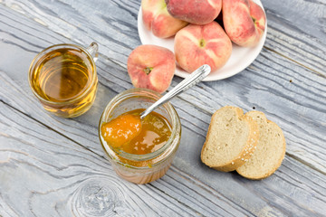 Peach jam, tea and bread close-up on a wooden table