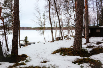 Natural landscape - forest, lake are under snow in spring in March
