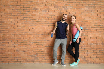 Sporty young people near brick wall