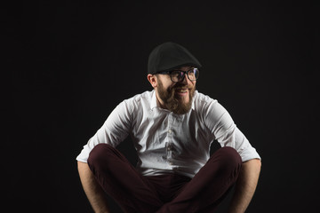 young handsome man in glasses with a beard and a mustache in a black cap and a white shirt...