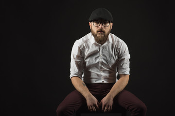 young handsome man in glasses with a beard and a mustache in a black cap and a white shirt...