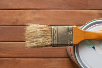 Paint  brush on can with wooden background, top view