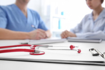 Stethoscope with clipboard on doctor's table, closeup