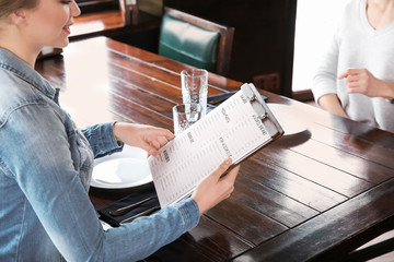 Young woman reading menu in restaurant
