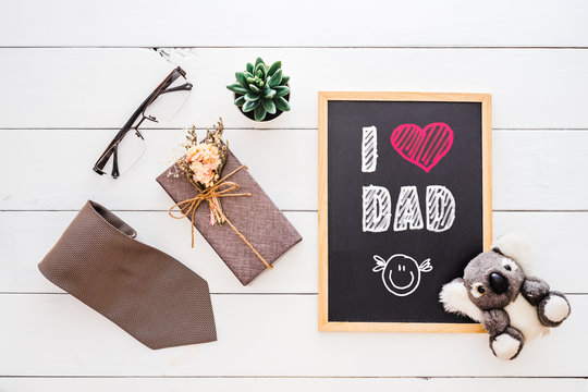 Happy Father's day concept. Flat lay image of gift box, necktie, glasses, rose flower and chalkboard with I Love Dad text.