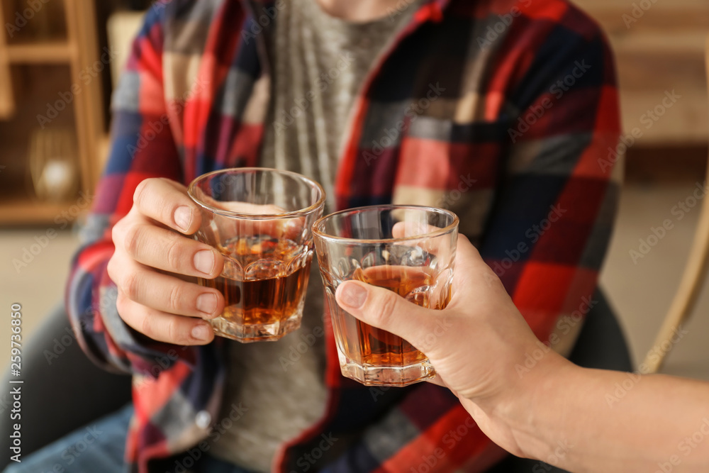 Wall mural man and woman clinking glasses of cold whisky, closeup