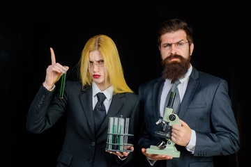 Science. Experiment. Chemistry. Test tubes. Education. Biology. Woman with chemical test tubes. Bearded man with microscope. Laboratory. Progressive school. Analysis. Assistant.