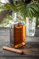 Bottle of cold whiskey with cigar on wooden table