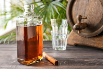 Bottle of cold whiskey with cigar on wooden table