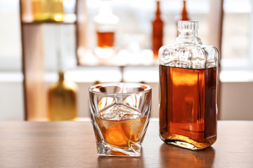Glass and bottle of cold whiskey on table in bar