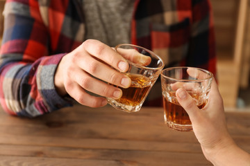 Man and woman clinking glasses of cold whisky, closeup
