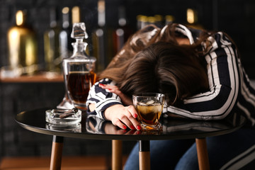 Drunk woman with whisky at table in bar