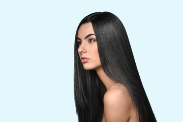 Portrait of beautiful young woman with healthy long hair on color background