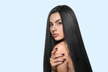 Portrait of beautiful young woman with healthy long hair on color background