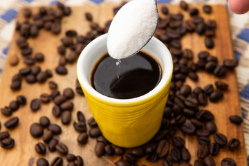 small cup of coffee being sweetened.