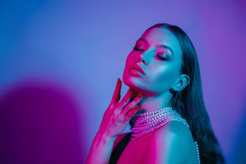 High fashion model in colorful bright neon lights posing at studio. Portrait of beautiful girl with...