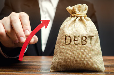 A bag with the word Debt and an up arrow in the hands of a businessman. Receivables. The growth of...