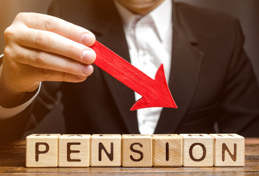 A man holds an arrow down over wooden blocks with the word Pension. Fall / reduction pension payments. Retirement. Financing retirees. Reduction of the pension fund. The low size of pensions.