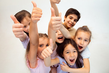 The portrait of happy cute little kids boy and girls in stylish casual clothes looking at camera against white studio wall. Kids fashion and human emotions concept