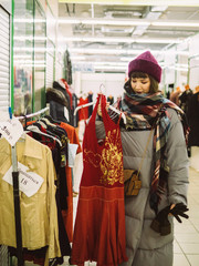 Young woman is browsing a rail of clothes at mall store