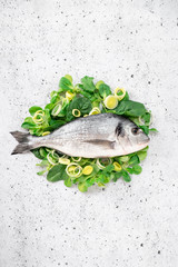 Fresh sea Bream fish on spinach and green onions. The concept of healthy diet seafood, top view and copy space