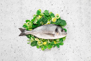 Fresh sea Bream fish on spinach and green onions. Healthy seafood concept, top view and copy space