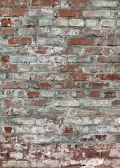 The wall of the old house with a worn surface. The shabby texture of bricks and cracked lime on the background of the curve of masonry.
