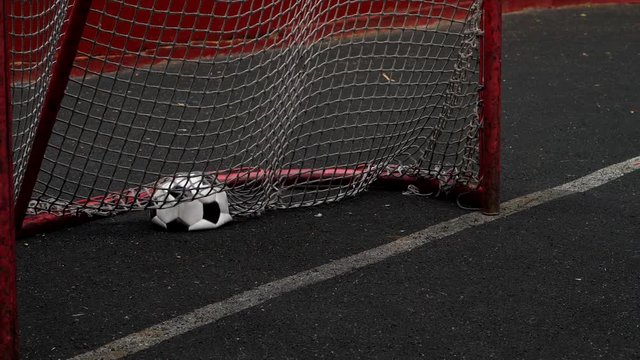 Outworn and deflated but rather new soccer ball run into small gate, check one point. Crumple ball fly inside goal gate of five-o-side size, nobody protect it. Slow motion shot