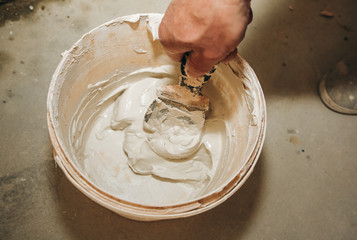 Man is mixing spackling paste putty in the bucket. Grind of wall. Maintenance repair works...