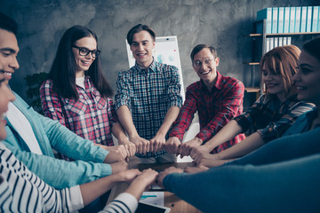 Positive cheerful colleagues managers partners show strength power unity placing hands fists shape...