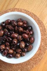 Italian Taggiasche olives in a bowl on wooden table