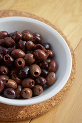Italian Taggiasche olives in a bowl on wooden table