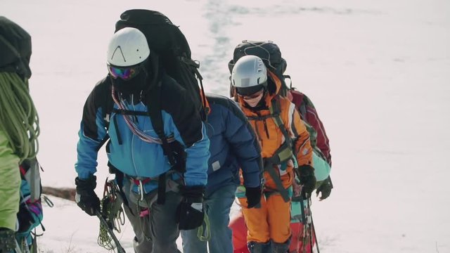 Coordinated team of climbers climb up the mountain in deep snow fatigue