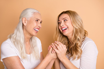 Close-up portrait of nice-looking winsome sweet tender gentle attractive charming cheerful cheery dreamy ladies holding hands trust isolated over beige pastel background