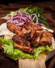 grilled barbecue meat served on a wooden Board with fresh vegetables and spices